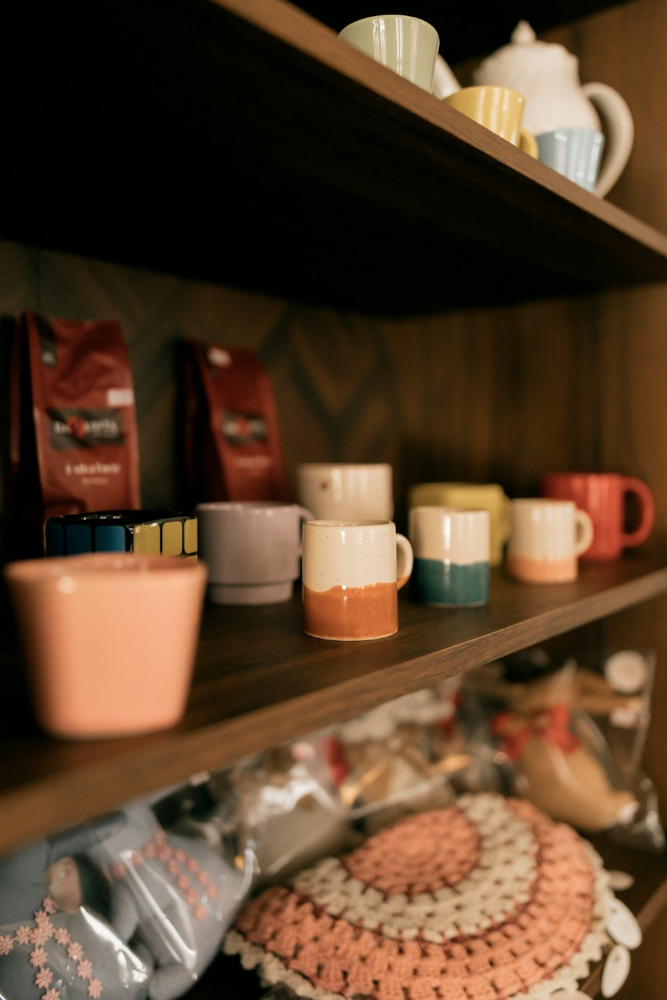 Pastelowe ceramiczne kubki na ciemnych drewnianych półkach.